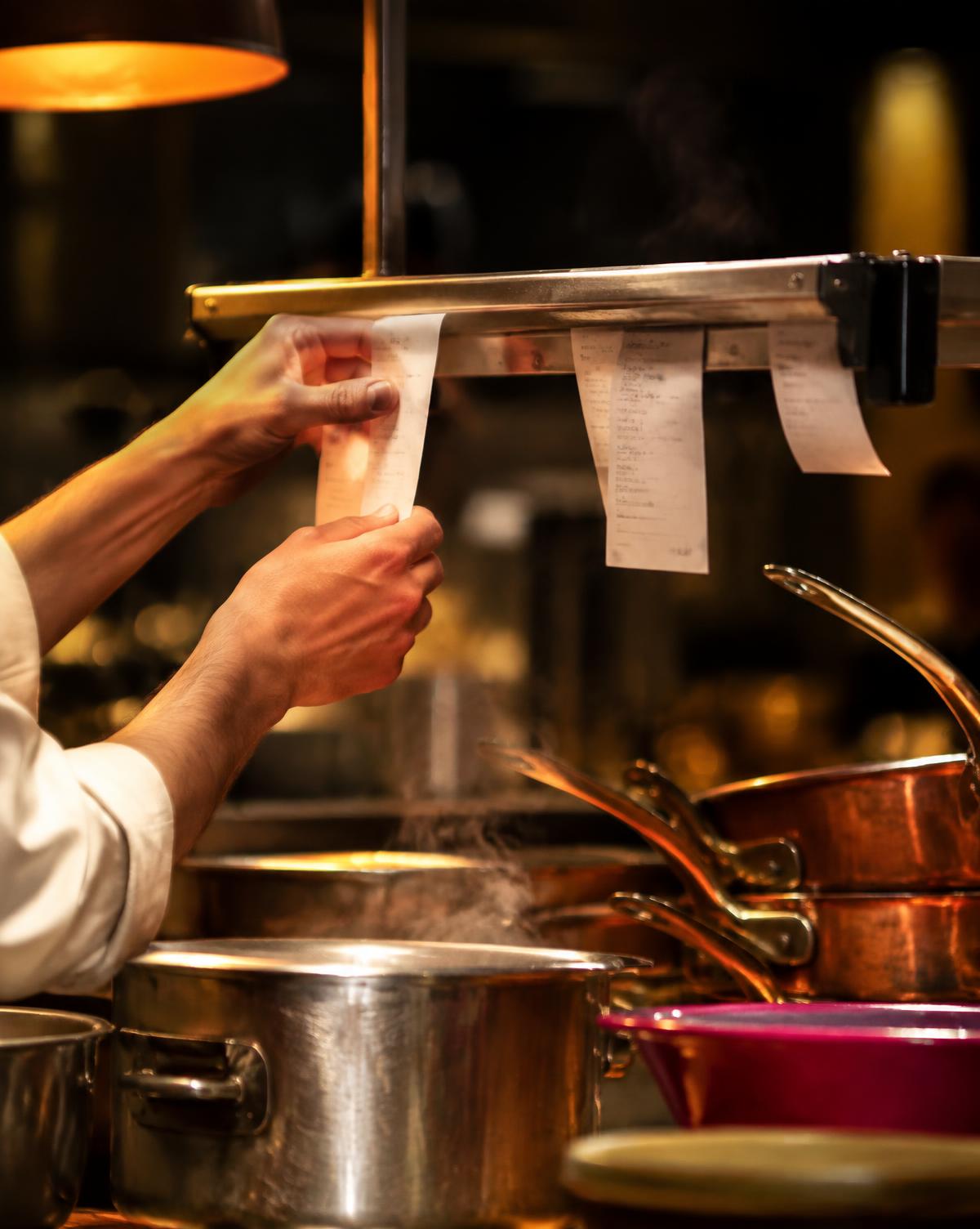 Cocinero tomando una comanda del riel de la cocina